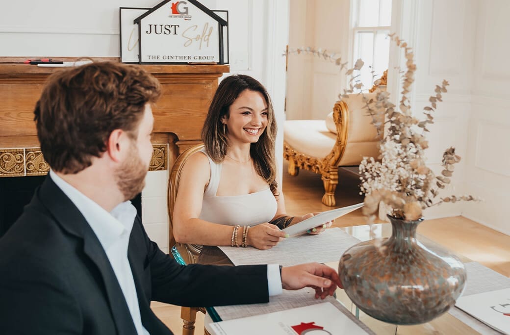 Real estate agents celebrate a "Just Sold" sign with clients in Winston-Salem.