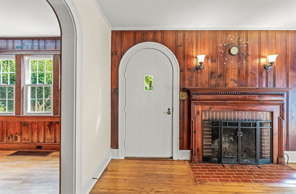Arched white door in wood-paneled room with fireplace, Winston-Salem home