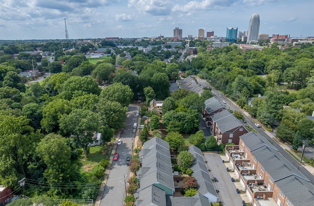 Aerial view of Winston-Salem homes and skyline, with trees.