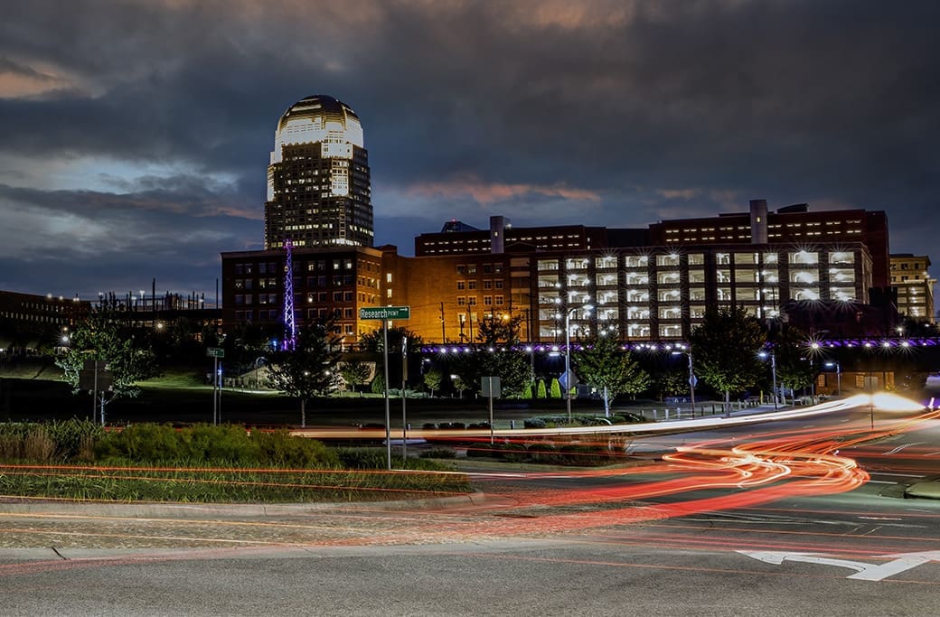 Winston-Salem skyline at night with traffic on Research Parkway