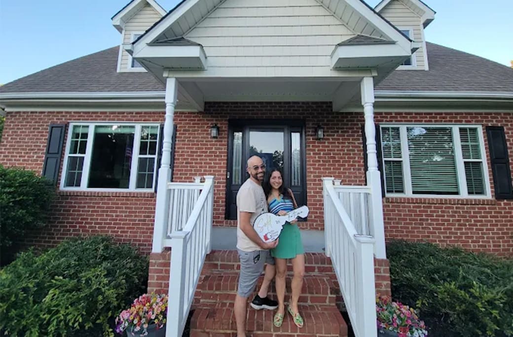 Winston-Salem home sellers with a sold sign from The Ginther Group